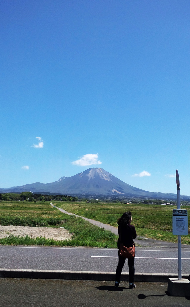 大山とバスを待つ人