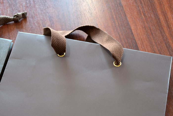 紙袋の紐を通す穴に金の留め金を追加。