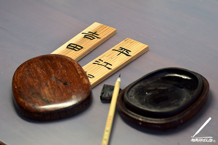 木札に隷書で名前を書き入れる